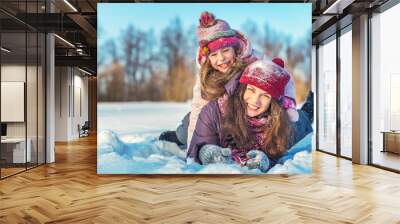 Little girl and her mother playing outdoors at sunny winter day. Active winter holydays concept. Wall mural