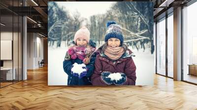 Little girl and her mother playing outdoors at winter day. Active winter holydays concept. Wall mural