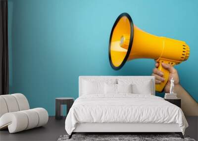 Hand holding small megaphone isolated blue background studio photo with copy space without watermark Wall mural