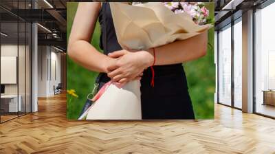 A girl in a black dress with a bouquet of flowers in her hands. Detailed photo Wall mural