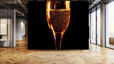 A glass of golden water is isolated on a black . Wall mural