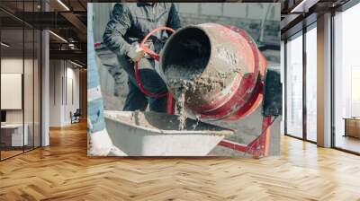 Worker pouring concrete with cement mixer at construction site, closeup Wall mural