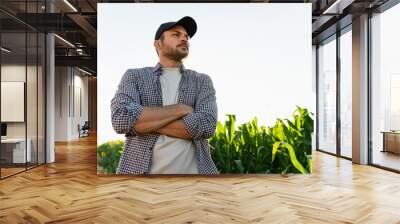 Bearded farmer in a cap and a plaid shirt against the background of a corn field Wall mural