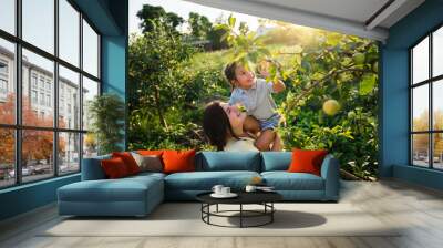 Caucasian mother and her Asian daughter in the apple garden in summer Wall mural