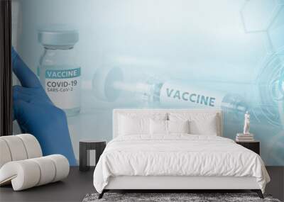 Doctor in a protective suit against the background of a syringe with the inscription Vaccine. Coronavirus vaccine development Wall mural