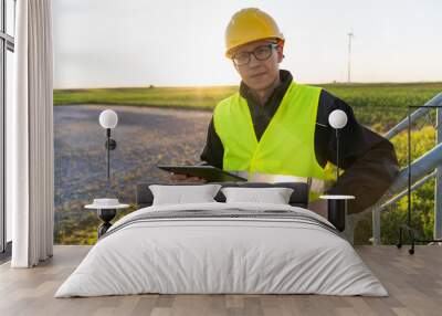 Engineer with digital tablet works on a field of wind turbines Wall mural