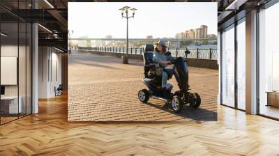 Woman tourist riding a four wheel mobility electric scooter on a city street.	 Wall mural