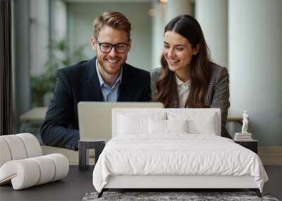 Smiling colleagues working together on a laptop during a business meeting in a modern office. They appear engaged and productive, surrounded by a bright, welcoming environment.

 Wall mural