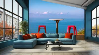 Two cafe chairs and a table on a hillside with an uninterrupted view of the ocean on a clear, blue sky, sunny morning. Copy space. Wall mural