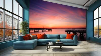 Vibrant orange and pink pastel color sunset over fishing piers. Perfectly still water Wall mural