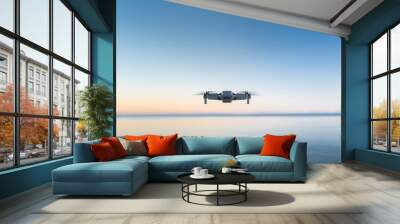 A micro drone hovers in the air above a water horizon  Wall mural