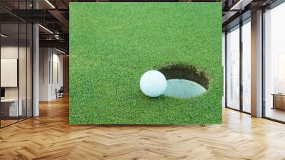 A golf ball very close to a hole Wall mural