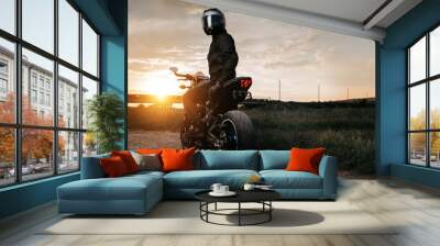 Back view of biker sitting on motorcycle in sunset on the country road. Wall mural