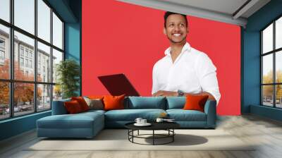 Smiling african american young man holding notebook over red background. Wall mural