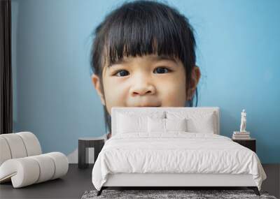 A headshot portrait of a cheerful baby Asian woman, a cute toddler little girl with adorable bangs hair, a child wearing a purple sweater smiling and looking to the camera. Wall mural