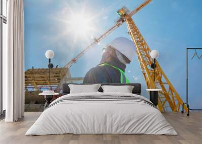 architect or construction worker or civil engineer or foreman with hard hat and safety vest on construction site  with crane and sun flare Wall mural