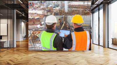 construction worker  engineer architect team at work on major construction site with computer tablet hardhat and safety vest Wall mural