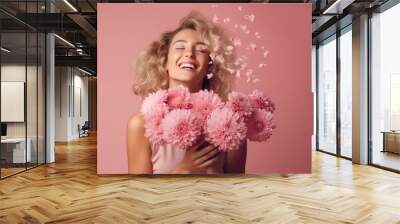 Happy woman in a bright pink dress is smelling a bunch of pink and red flowers Wall mural