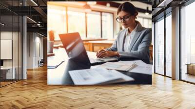 Young business woman employee or executive manager using computer looking at laptop and check  business papers  for online training working in office. Wall mural