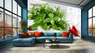 Bunch of aromatic herbs in mortar on kitchen table Wall mural