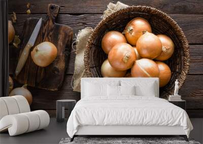 Fresh onion in basket on wooden table, top view Wall mural