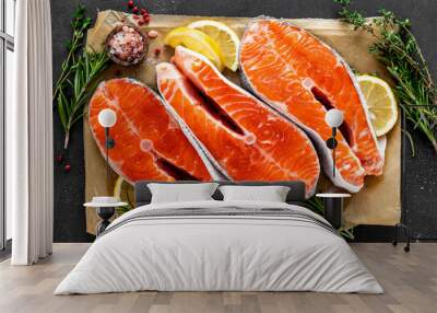 Fresh raw salmon fish steaks on black background with ingredients for cooking. Closeup. Top view Wall mural