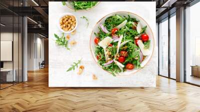 Fresh vegetable salad with arugula, tomato, onion, parmesan cheese and cashew nuts. Top view Wall mural