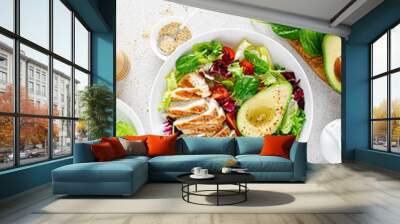 Grilled chicken meat and fresh vegetable salad of tomato, avocado, lettuce and spinach. Healthy and detox food concept. Ketogenic diet. Buddha bowl dish on white background, top view Wall mural