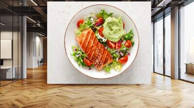 Grilled salmon fish fillet and fresh green lettuce vegetable tomato salad with avocado guacamole. Top view Wall mural