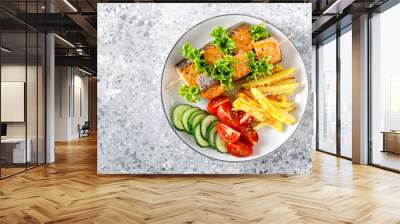 Grilled salmon kebab on skewers with baked potato, fresh cucumbers and tomatoes Wall mural