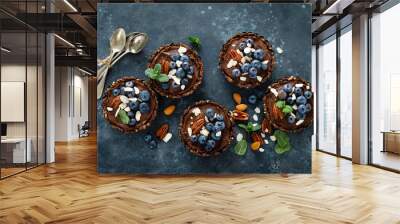 Healthy raw vegan dessert dates tartlets with chocolate cream of cashew, decorated with almond, pecan nuts and fresh blueberry Wall mural