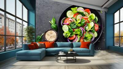 Healthy vegetable salad of fresh tomato, cucumber, onion, spinach, lettuce and sesame on plate. Diet menu. Top view. Wall mural