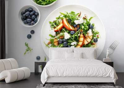 Peach, blueberry and arugula fresh fruit salad with cheese and almond nuts, top view Wall mural