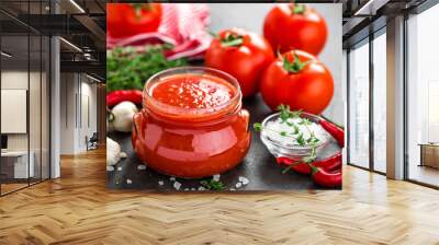 Tomato paste, puree in glass jar and fresh tomatos on dark background. Hot vegetable sauce with chili pepper and tomatoes Wall mural