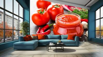 Tomato paste, puree in glass jar and fresh tomatos on dark background. Hot vegetable sauce with chili pepper and tomatoes Wall mural