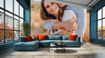 young couple happy girl and guy are hugging and looking at the camera lens Wall mural