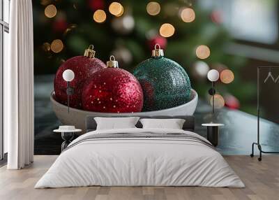 A bowl of shiny red and green Christmas tree ornaments on a table. Concept of festive holiday colors. Wall mural