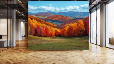 A scenic view of rolling hills blanketed in a mosaic of red, yellow, and orange leaves, with a clear blue sky. Concept of autumn landscapes and natural beauty. Wall mural