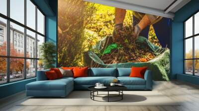 Cleaning in the garden. The concept of care for cleanliness and order in the garden. The man cleans the leaves, old branches throwing them into the bag. Sweeping dust and leaves. Wall mural