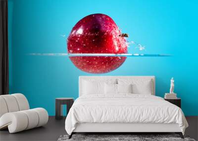 Fresh and delicious red apple isolated on a blue background. Red apple dropping in water and creating a splash. The concept of healthy eating, consuming fruit. Wall mural