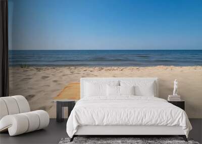 A serene beach scene featuring an orange towel on sandy shore. Wall mural