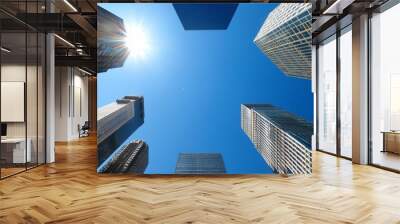 A view of tall skyscrapers against a clear blue sky with sunlight. Wall mural