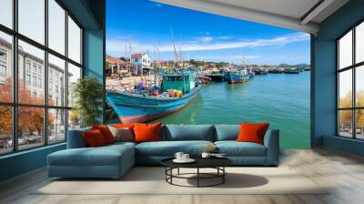 Colorful fishing boats docked at a vibrant harbor under a clear sky. Wall mural