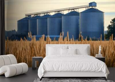 Silos stand amidst golden wheat fields at sunrise. Wall mural