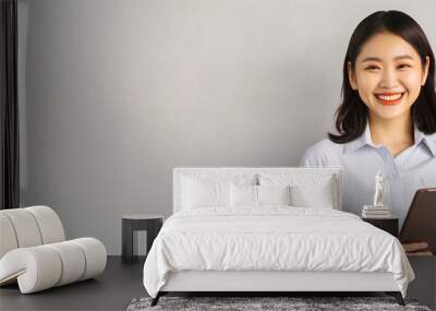 young Asian businesswoman stands and smiles while holding a tablet computer isolated on a white background. A panoramic banner with copy space area for text or a message Wall mural