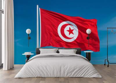 Tunisia flag waving in the wind against a blue sky background Wall mural