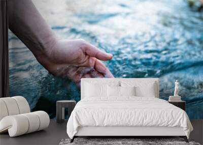 A female hand touching the river water Wall mural