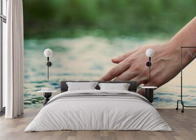 A female hand touching the river water	 Wall mural