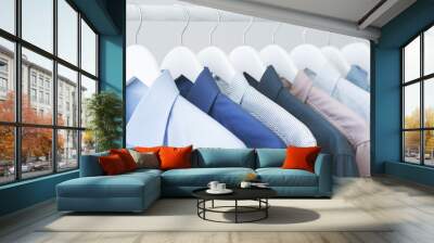 Assorted blue shirts hanging on wooden hangers Wall mural