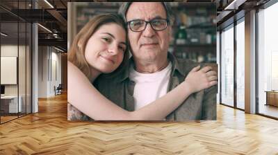 Cute young daughter embracing her father with love Wall mural